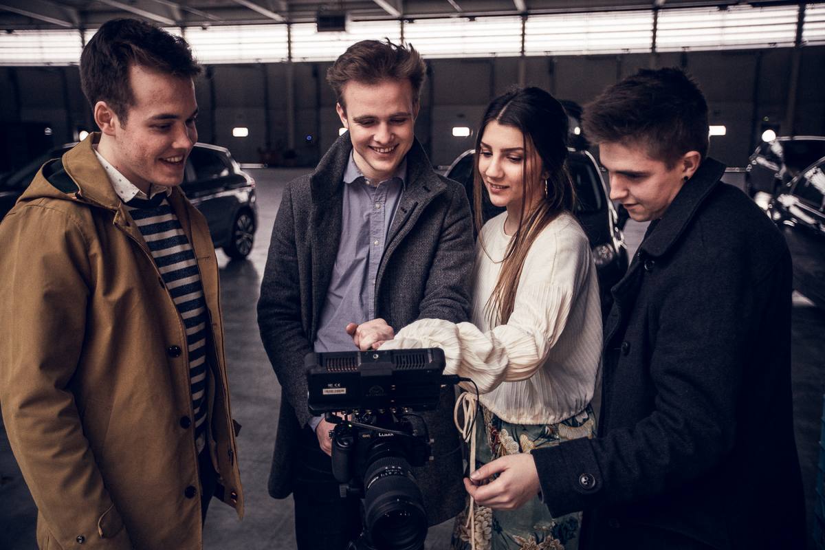 Vier bandleden bekijken samen de opnames op het camerascherm