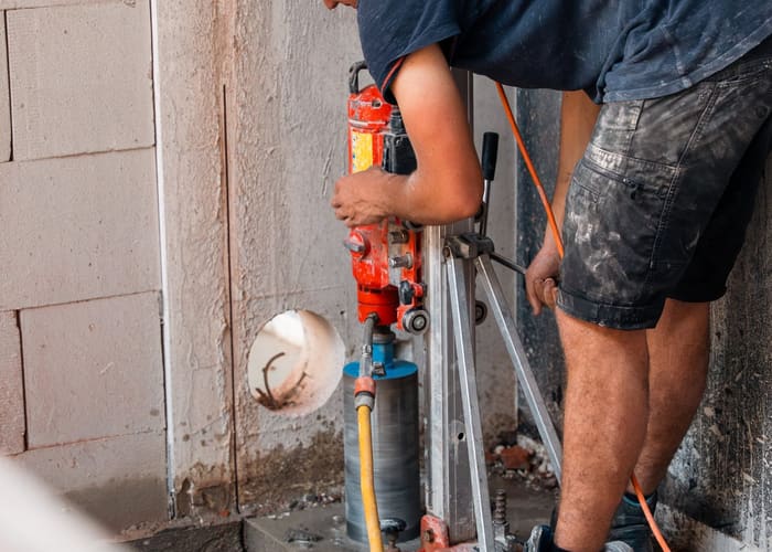 Een arbeider boort met een kernboor door een muur