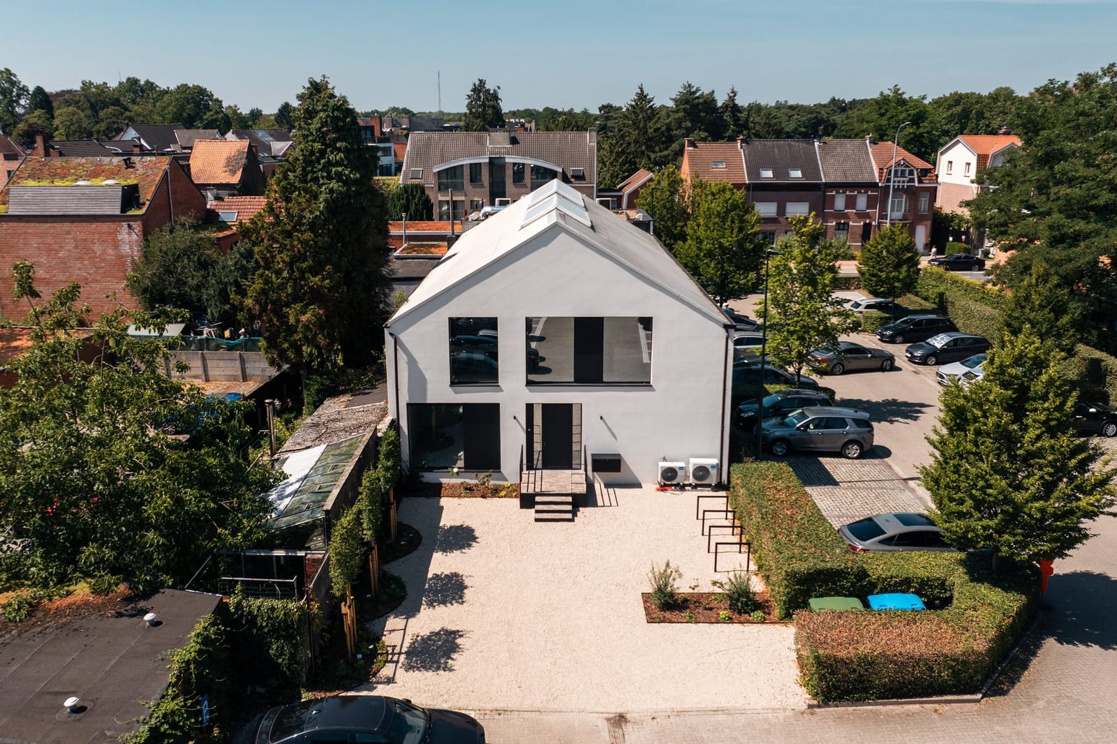 Luchtbeeld van het afgewerkte witte praktijkgebouw met de parking ervoor