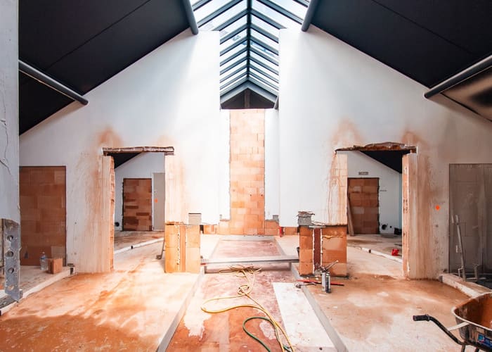 Twee nieuwe doorgangen in ruwbouw, met stutten en zonlicht op de vloer