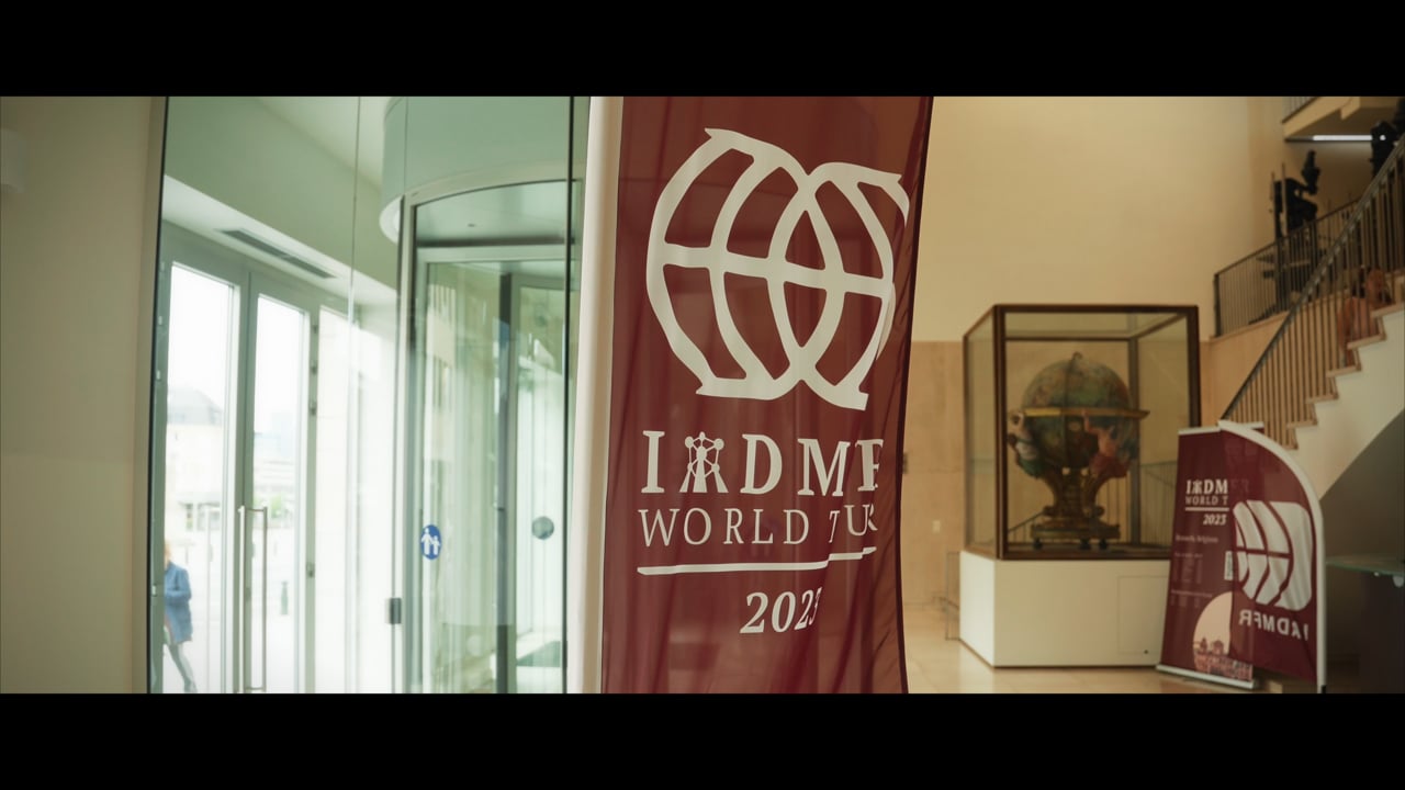 Congreszaal met een rood banner van de IADMFR World Tour 2023