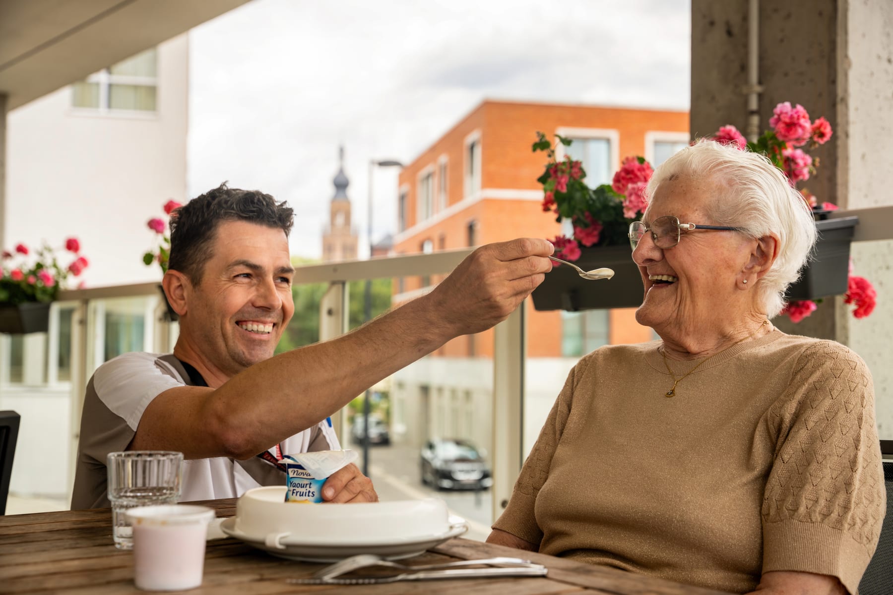 Zorgverlener die een oudere vrouw helpt bij het eten op een terras
