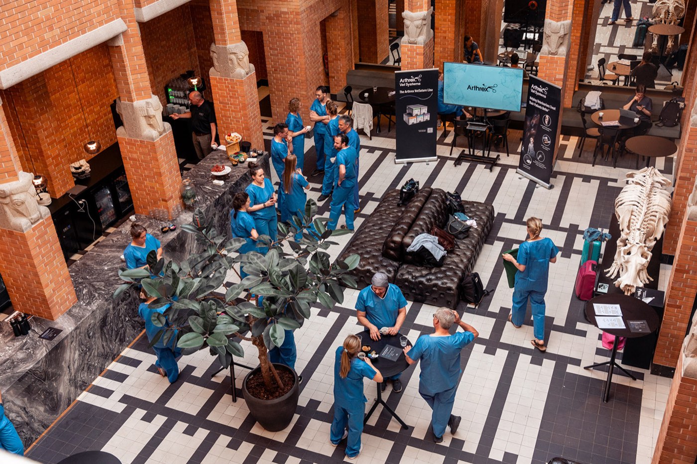 Bovenaanzicht van een congreshal waar zorgprofessionals in operatiekledij samenkomen