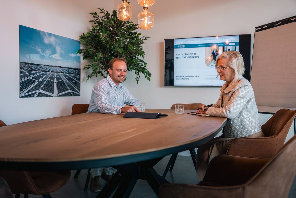 Wout Goos in gesprek met dr. Inge Wouters aan de vergadertafel