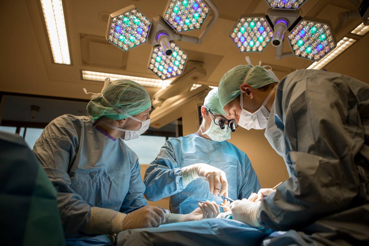 Drie chirurgen aan het werk onder de operatielampen
